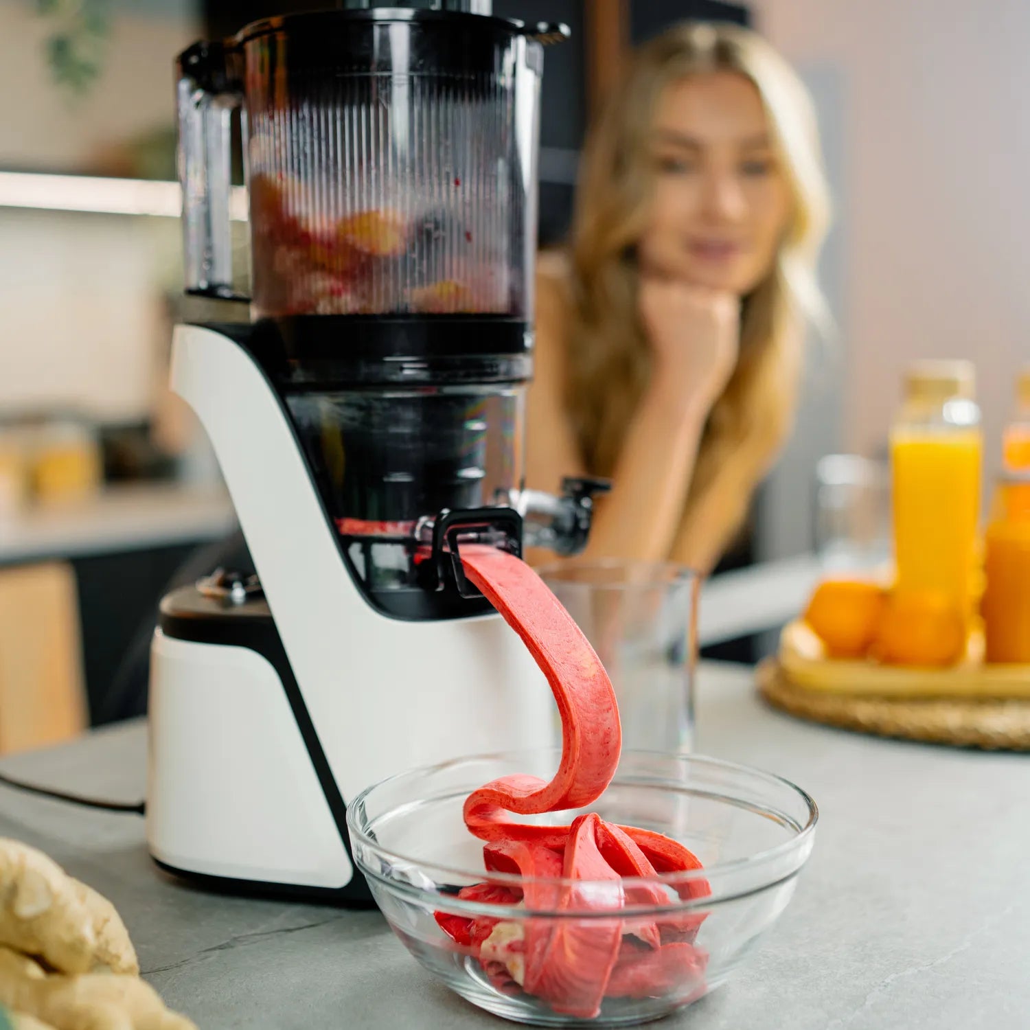 Canoly C16 cold press masticating juicer processing greens and tomatoes, with dry pulp ejection and slow extraction, white