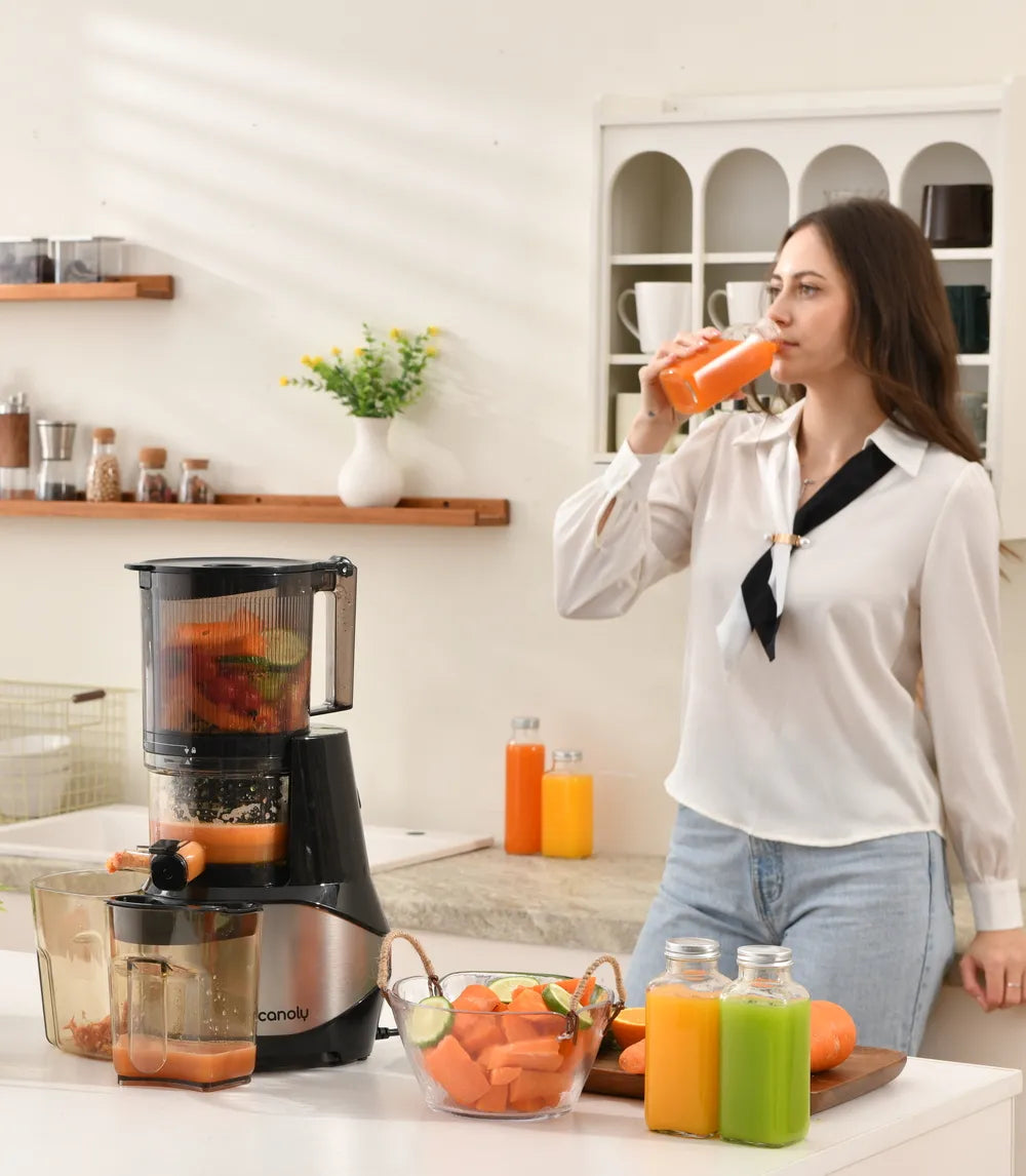 In the cozy kitchen, a young girl sips juice from the Canoly C09 cold-pressed slow juicer. Next to it are fresh fruits and bottled juices.